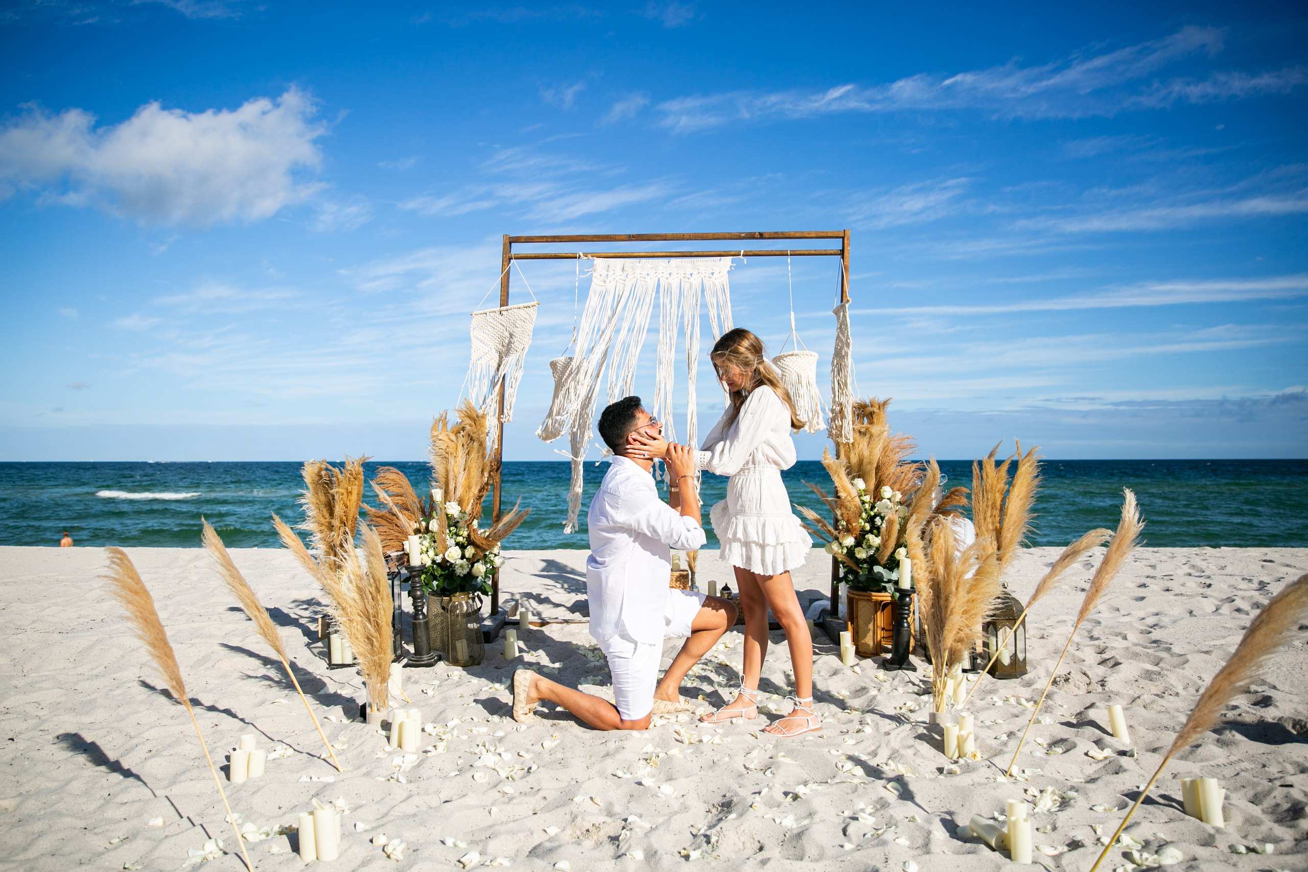 Proposal under a wooden macramé arch with pampas grass on the beach