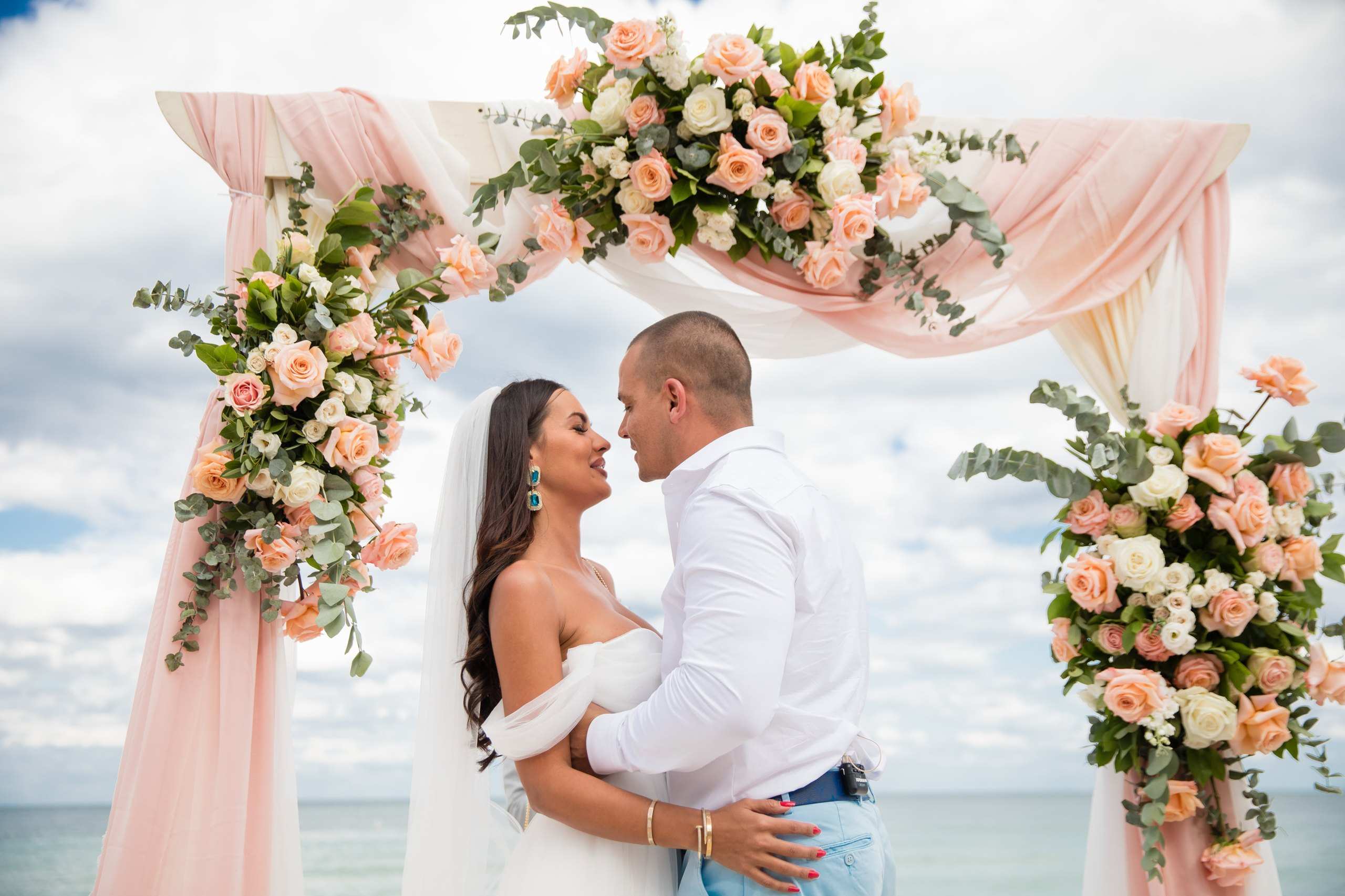 Couple under a blush floral arch