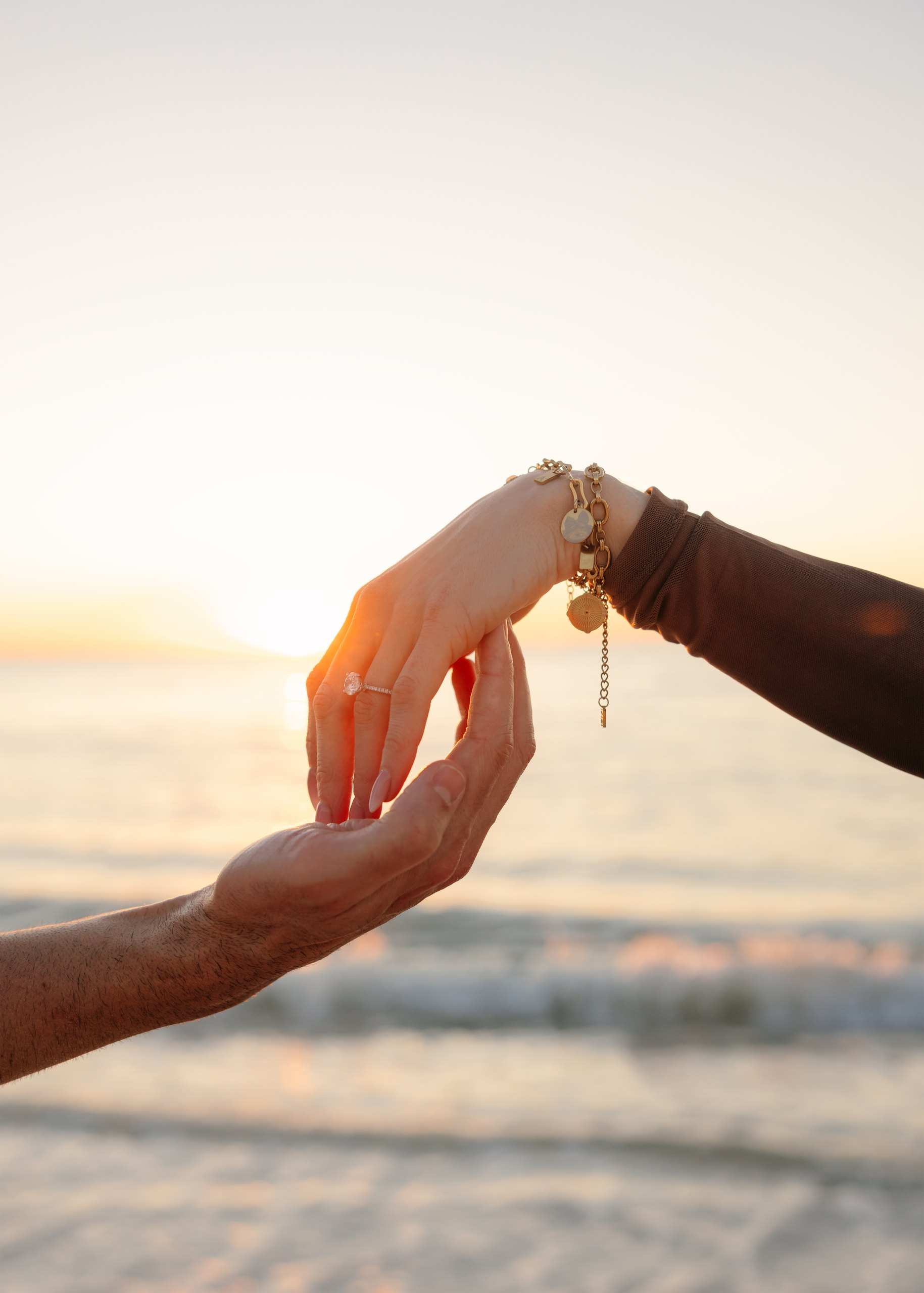 Hands with an engagement ring against the evening sky