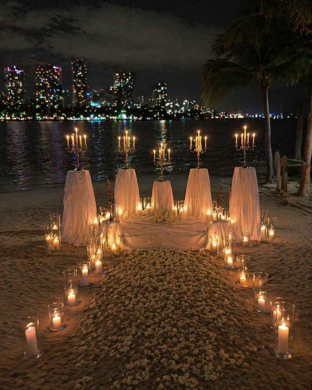 Aisle of candles and white fabric leading to gold candelabras