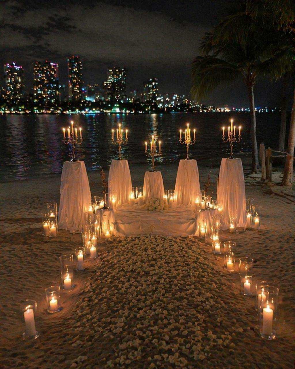 Aisle of candles and white fabric leading to gold candelabras
